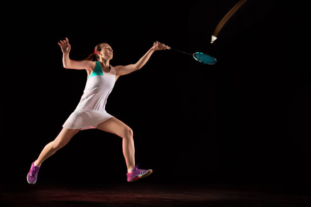 istock Young woman playing badminton isolated on black studio background 1157320964