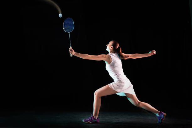 istock Young woman playing badminton isolated on black studio background 1157320971