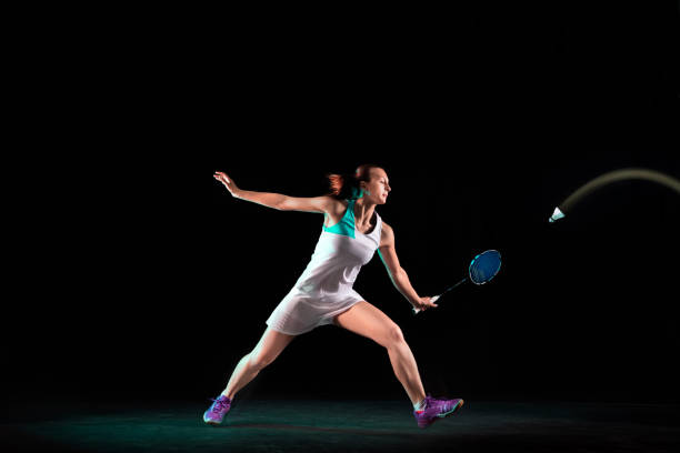 istock Young woman playing badminton isolated on black studio background 1157320979