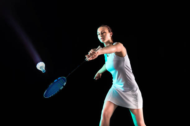 istock Young woman playing badminton isolated on black studio background 1157320988