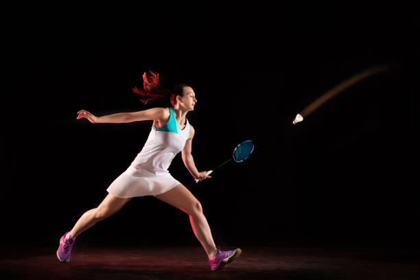 istock Young woman playing badminton isolated on black studio background 1157320990