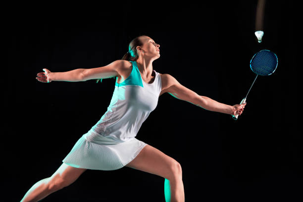 istock Young woman playing badminton isolated on black studio background 1157321000