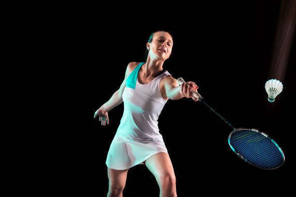 istock Young woman playing badminton isolated on black studio background 1157321001