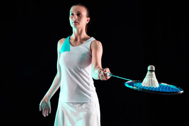 istock Young woman playing badminton isolated on black studio background 1157321008