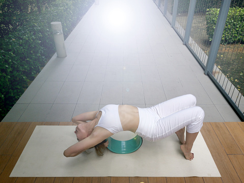 A lady using yoga wheel performing yoga pose, Setu Bandha Sirsasana at the park.