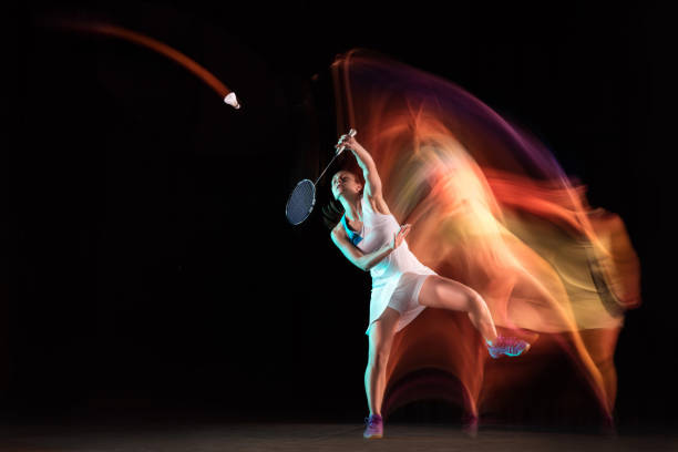 istock Young woman playing badminton isolated on black studio background 1157322581