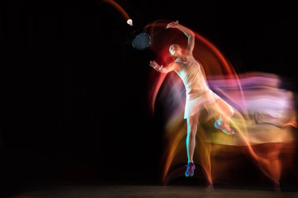 istock Young woman playing badminton isolated on black studio background 1157322612