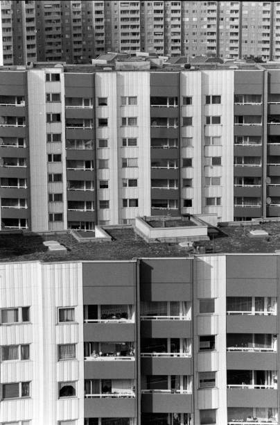 soviet high rise buildings in east berlin with many windows an balconies of a city apartment block strung together standing close to each other house facade old photo shot on 35mm black and white film - east berlin germany plattenbau apartment skyscraper imagens e fotografias de stock