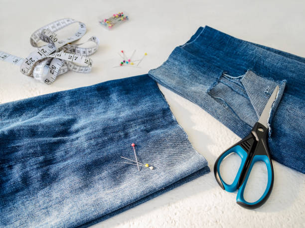 pant leg with a large hole cut off with scissors from a blue jeans folded in a half. making denim shorts. on a white. - short cut imagens e fotografias de stock