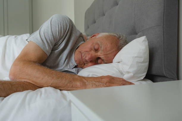 Active senior man sleeping in bed in bedroom stock photo