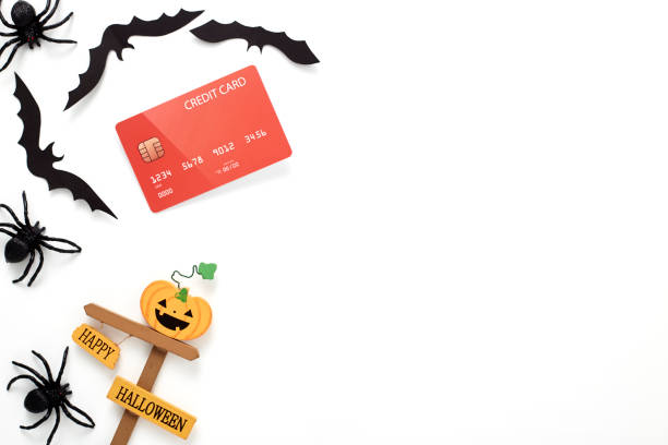Top view aerial image of decoration Happy Halloween day background concept.Flat lay accessories essential object to party the pumpkin and credit card, Black spider, bats paper on white wooden.Space for creative design.