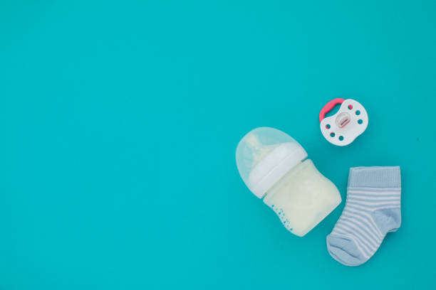 Top view of unisex newborn baby necessities Set for a newborn nipple bottle and socks blue background top view baby goods stock pictures, royalty-free photos & images