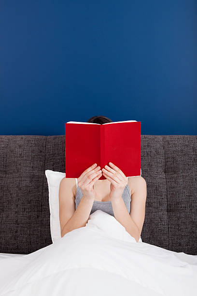 istock A woman intently reading a book in bed 115732902
