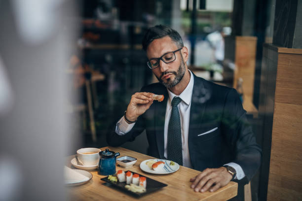 istock Businessman eating sushi with hands 1157330802
