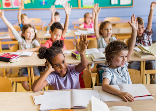 istock Large group of happy elementary students know the answer to teacher's question in the classroom. 1157337002