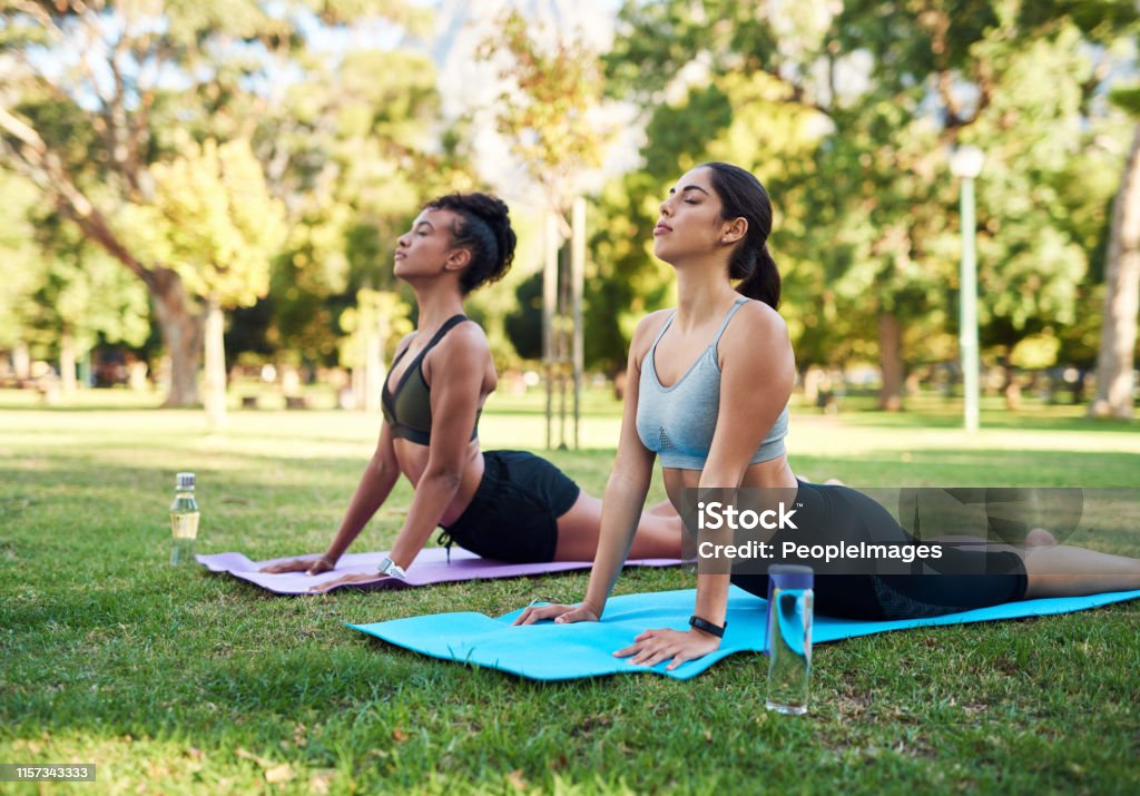 Ooo, I can definitely feel that Cropped shot of two attractive young women holding a yoga pose in the park during the day Yoga Stock Photo