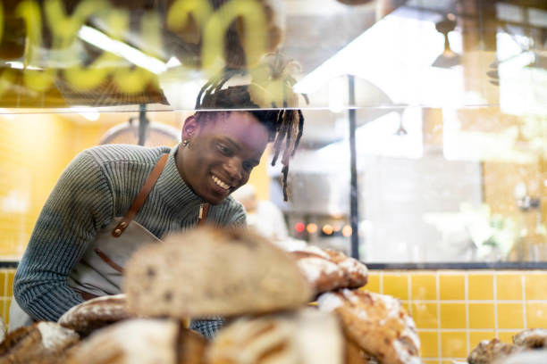 istock Male baker putting breads inside a bag in the bakery 1157343506