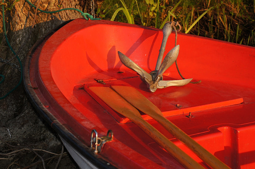 Rowing boat with paddle and anchor on the lake shore