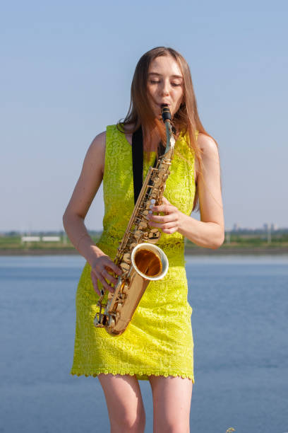 istock Young woman with saxophone with nature background 1157343825
