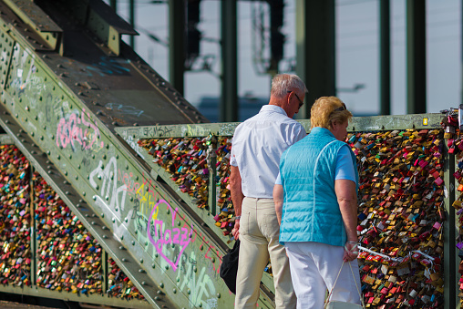 Cologne, Germany - September 22, 2016: real love - couple hand in hand at the bridge of love padlocks. This bridge - the Hohenzollern bridge in Cologne Germany is full of love padlocks. A lot of young couples have made this padlocks over the years, so its a sightseeing of Cologne to walk over this bridge and read the messages.