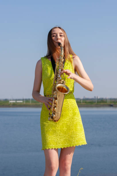 istock Young woman with saxophone with nature background 1157345050