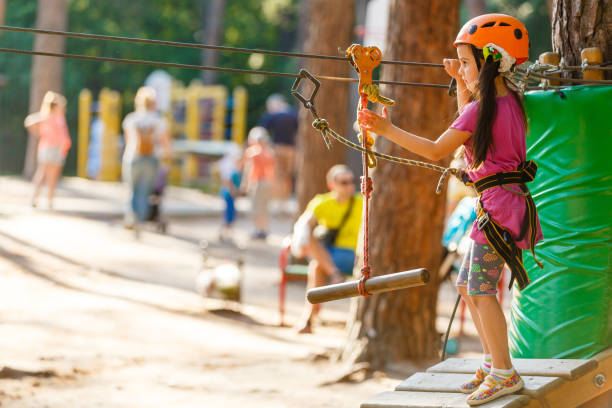 menina feliz da escola que aprecia a atividade em um parque de escalada da aventura em um dia de verão - education high up sport sports helmet - fotografias e filmes do acervo