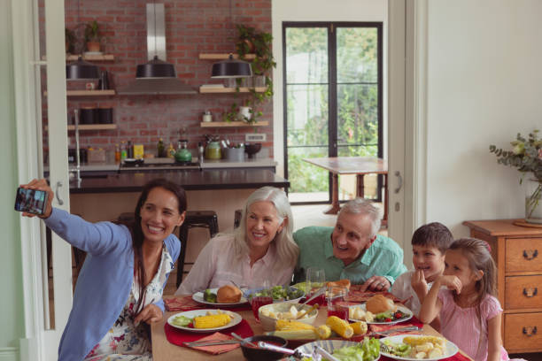 istock Multi-generation family taking selfie with mobile phone while having food on dining table 1157345302