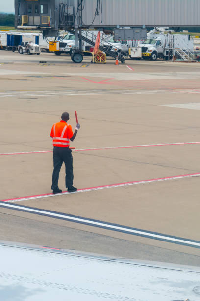 istock Worker at the Airport Dressing a Red Safety Jacket on Blur Background 1157345414