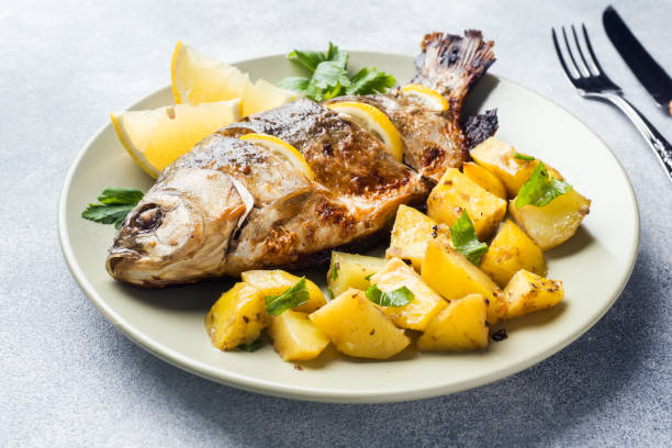Baked fish carp with lemon greens and potatoes on a plate. Baked fish carp with lemon greens and potatoes on a plate carp stock pictures, royalty-free photos & images