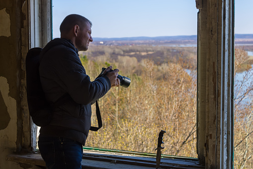 Tourist photographs the terrain from the window of an abandoned building