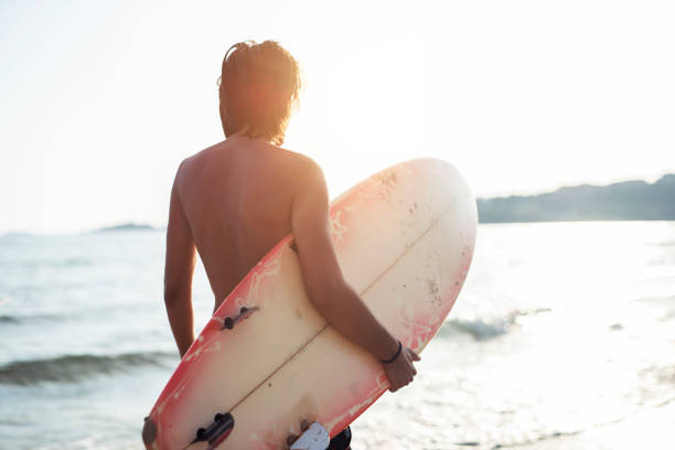 istock Surfer walking on the beach at sunrise. 1157351793
