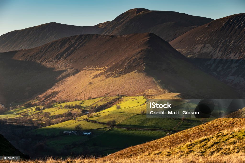 Beautiful Autumn Fall landscape image of sun beams lighting up small area of mountain side in Lake District whilst rest of area is in darkness with Robinson and Dale Head in background Stunning landscape image of sun beams lighting up small area of mountain side in Lake District whilst rest of area is in darkness with Robinson and Dale Head in background Autumn Stock Photo