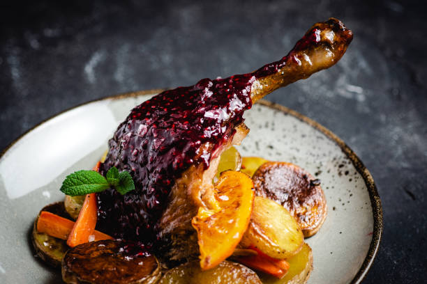 Roasted Goose Leg with Potatoes, Carrots and Oranges Roasted Fat Goose Leg with Potatoes, Carrots and Oranges confit stock pictures, royalty-free photos & images