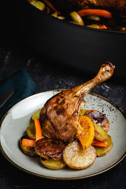 Roasted Chicken Leg with Potatoes, Carrots and Oranges Roasted Chicken Leg Dish with Potatoes, Carrots and Oranges confit stock pictures, royalty-free photos & images