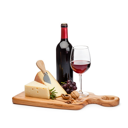 Cheese and wine: cutting board with cheese slices, grape and walnuts isolated on white background. A red wine bottle and a wineglass are behind the cheese tray. Useful copy space available for text and/or logo. High key DSRL studio photo taken with Canon EOS 5D Mk II and Canon EF 100mm f/2.8L Macro IS USM.