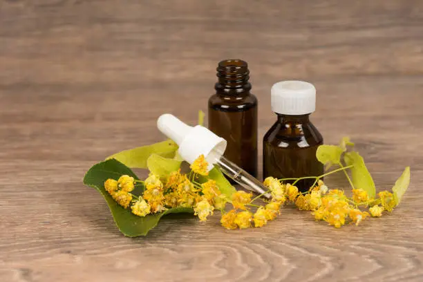 Linden blossom with dark brown glass bottle. Alternative medicine or folk healing concept.