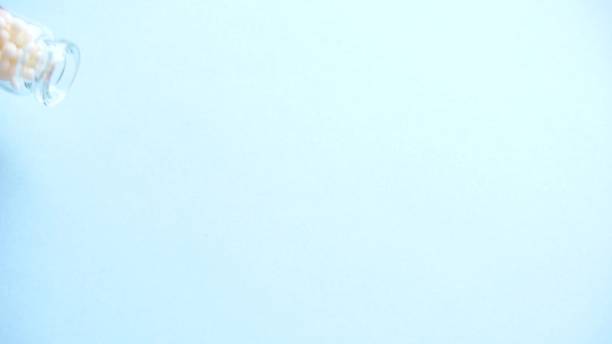 istock homeopathic globules roll on the blue background from glass bottle. Alternative Homeopathy medicine herbs, healtcare and pills concept. Top view. 1157355546