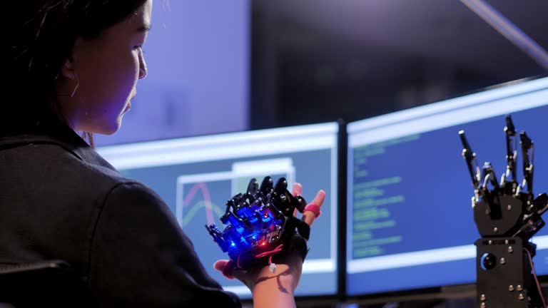 A futuristic Prosthetic Robot Arm by a teenage girl development engineer in a research laboratory at night of working late.Arm moves its fingers.Education,Technology,Teamwork,Working Late,Science and people concept.Education Topics.Industry 4.0