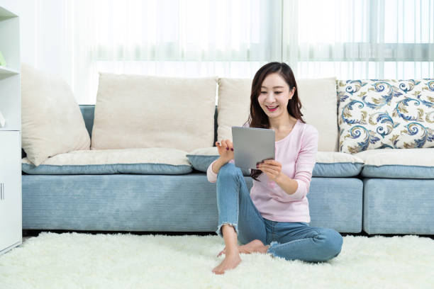 istock Beautiful woman sitting on floor and using digital tablet 1157358264