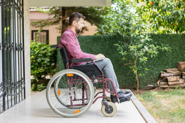 istock Disabled man in wheelchair using laptop at backyard 1157359709