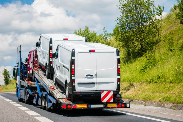 a flatbed truck loaded with two vans