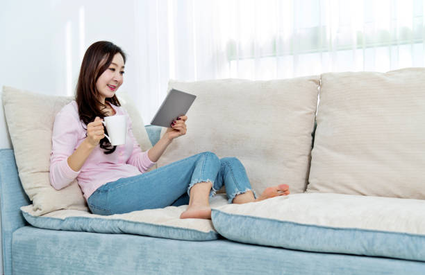 istock Beautiful woman sitting on the sofa and using digital tablet 1157360188