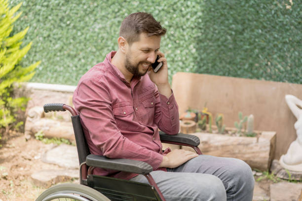 istock Disabled man in wheelchair using smartphone at backyard 1157365905