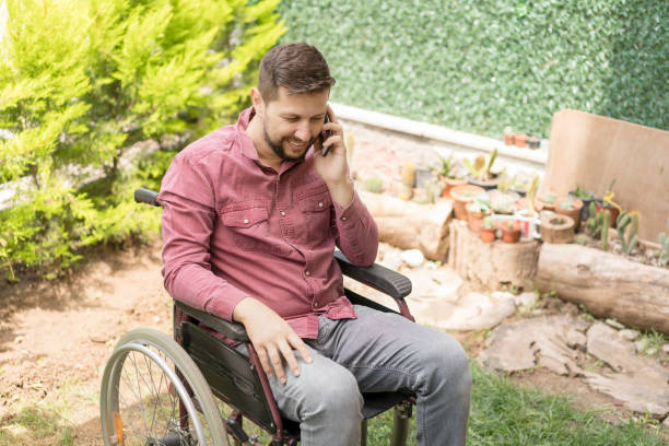 istock Disabled man in wheelchair using smartphone at backyard 1157365934