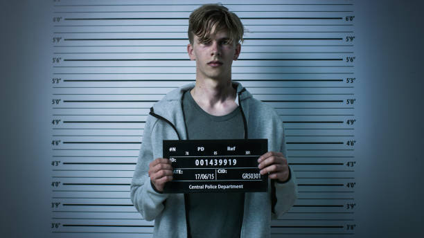 In a Police Station Arrested Drug Addict Teenage Posing for a Front View Mugshot. He is Heavily Bruised. Height Chart in the Background. In a Police Station Arrested Drug Addict Teenage Posing for a Front View Mugshot. He is Heavily Bruised. Height Chart in the Background. placard photos stock pictures, royalty-free photos & images