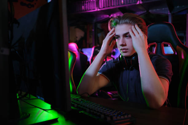 Professional young caucasian gamer playing online on his PC. He upset because of losing the game stock photo