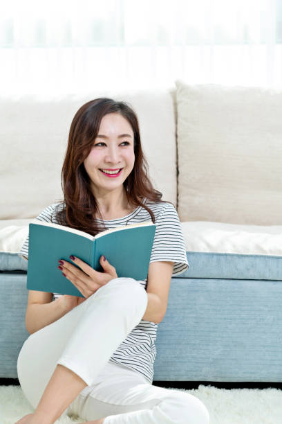 istock Beautiful woman sitting on floor reading book 1157372907