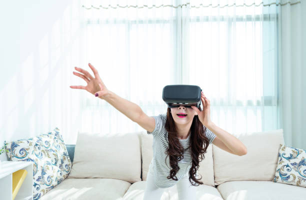 istock Woman wearing virtual reality simulator at home 1157377842