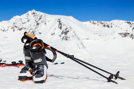 ski hardware equipment with skis, poles and boots resting on the snow with snowcapped mountain background