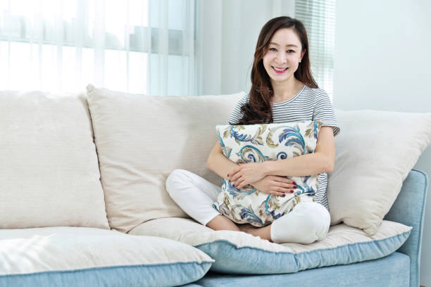 istock Smiling woman sitting on sofa 1157379133